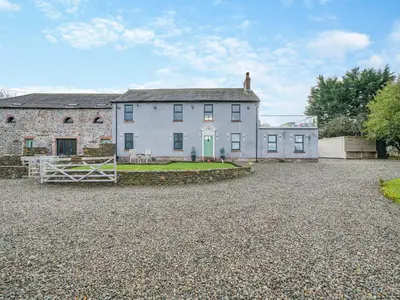a large house with a gravel driveway in front of it at North Plain Barn in Bowness-on-Solway