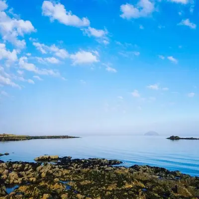 a body of water with rocks and a blue sky at Woodland Bay Hotel in Girvan