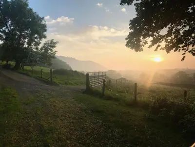 a fence on a field with the sun setting in the background at Carrick Beg Self Catering Holiday Accommodation with Hot Tub in Sulby