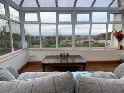 a living room with two couches and a table and windows at Carrick Beg Self Catering Holiday Accommodation with Hot Tub in Sulby