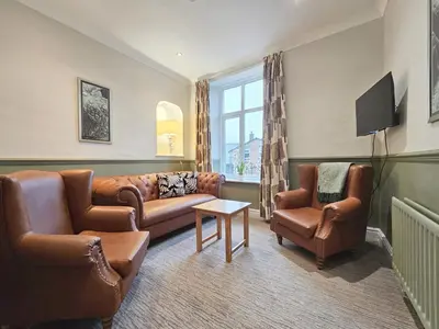 a living room with leather furniture and a tv at Derwent Manor Apartments in Keswick