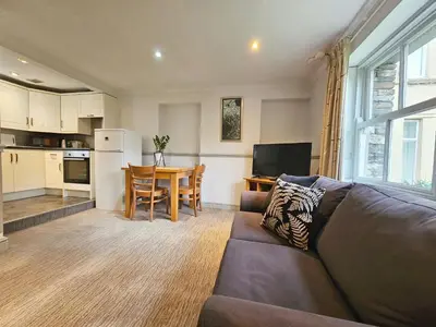 a living room with a couch and a table and a kitchen at Derwent Manor Apartments in Keswick