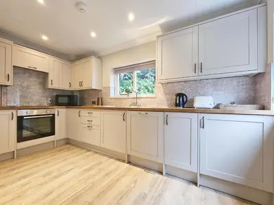 a kitchen with white cabinets and a wooden floor at Derwent Manor Apartments in Keswick