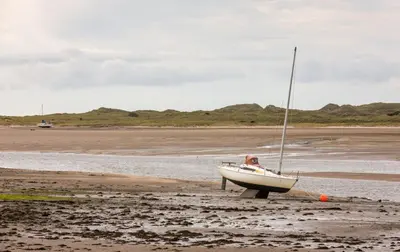 a sailboat sitting on the shore of a beach at The Inn at Ravenglass in Ravenglass