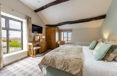 a bedroom with a large bed and a window at The Inn at Ravenglass in Ravenglass