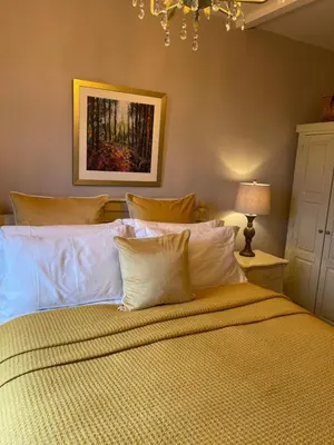 a bedroom with a large bed with white pillows at Woodend Cottage in Dumfries