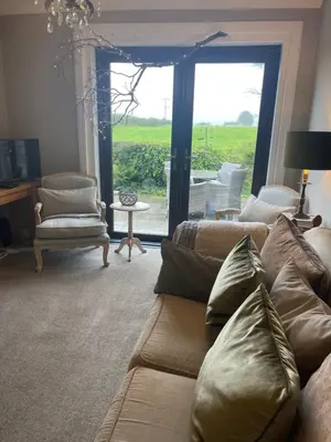 a living room with a couch and a large window at Woodend Cottage in Dumfries