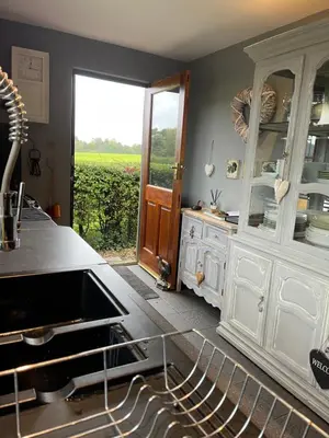 a kitchen with white cabinets and a view of a field at Woodend Cottage in Dumfries