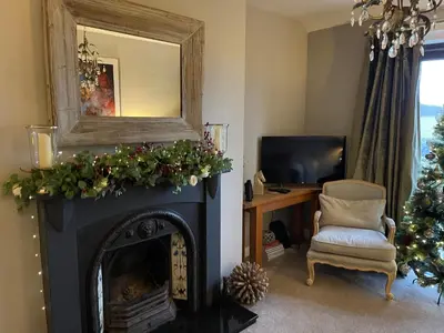 a living room with a fireplace and a christmas tree at Woodend Cottage in Dumfries
