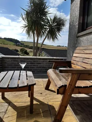 a wooden picnic table and bench on a patio at Leafield Holiday Home in Stranraer