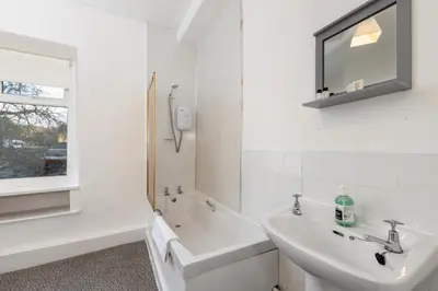 a white bathroom with a sink and a mirror at Muncaster Cottages in Ravenglass