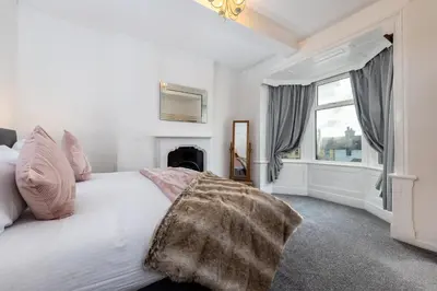 a bedroom with a white bed and a window at Muncaster Cottages in Ravenglass