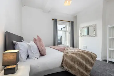 a bedroom with a white bed with pillows and a window at Muncaster Cottages in Ravenglass