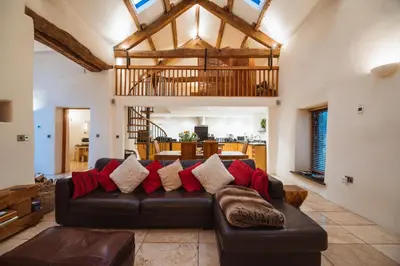 a living room with a brown leather couch with red pillows at The Lazy Fish in Cockermouth