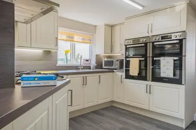 a kitchen with white cabinets and black appliances at Big White House in Cockermouth
