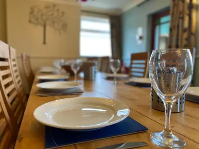 a wooden table with a plate and glasses on it at Big White House in Cockermouth
