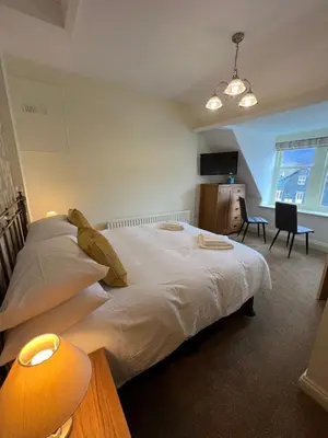 a bedroom with a large white bed and a desk at Brundholme in Keswick