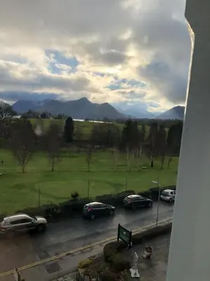 a group of cars parked on a road with mountains in the background at Brundholme in Keswick