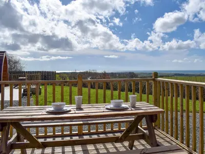 a wooden table with two cups and plates on a deck at Manx View-Uk1396 in Corney