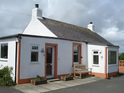 a white house with a bench in front of it at Bonshawbrae in Kirtlebridge