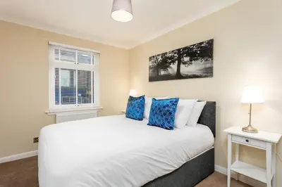 a bedroom with a large white bed with blue pillows at Cairn Suite - Donnini Apartments in Ayr