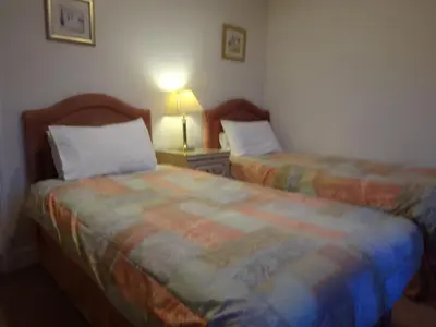 a bedroom with two beds and a lamp on a table at Aberdour Guest House in Dumfries