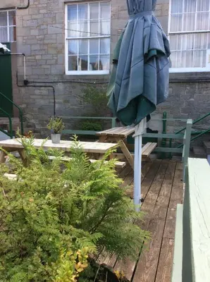 a large umbrella sitting on a bench in a garden at Eskdale Hotel in Langholm