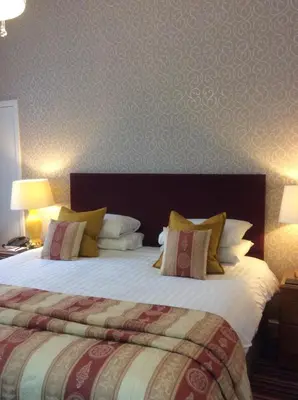 a hotel room with a large bed with pillows at Eskdale Hotel in Langholm