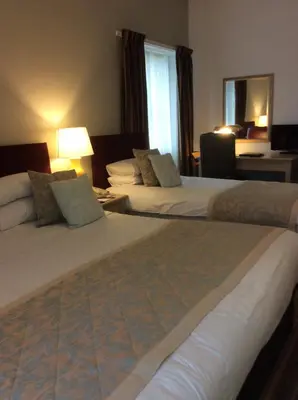 a hotel room with two beds and a window at Eskdale Hotel in Langholm