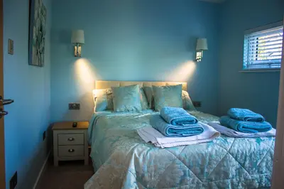 a blue bedroom with a bed with towels on it at Sunset Retreat Lodge with Hot Tub in Carsethorn