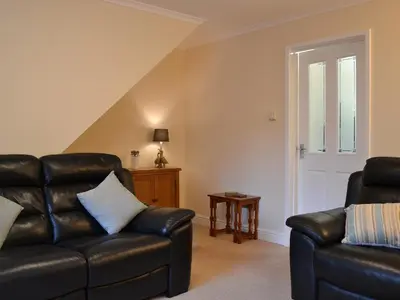 a living room with a leather couch and a table at Alan's Cottage in Cockermouth