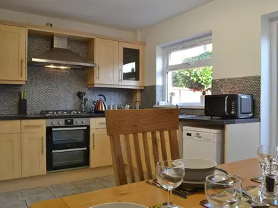 a kitchen with a wooden table with wine glasses at Alan's Cottage in Cockermouth