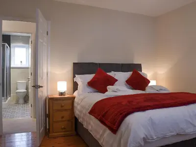 a bedroom with a large bed with red pillows at Alan's Cottage in Cockermouth
