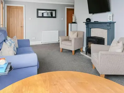 a living room with blue furniture and a fireplace at Wavecrest in Mainsriddle