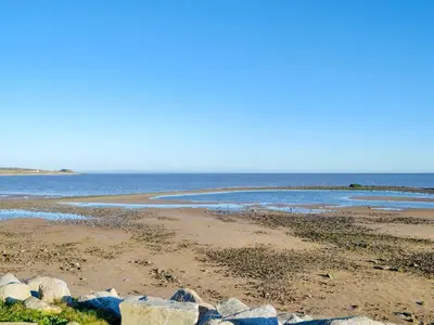 a beach with rocks and the ocean in the background at Wavecrest in Mainsriddle