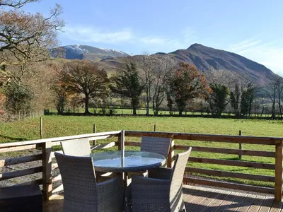 a table and chairs on a deck with a view of a field at Watches - Uk13544 in Bassenthwaite
