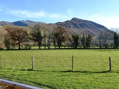 a fence in a field with mountains in the background at Watches - Uk13544 in Bassenthwaite