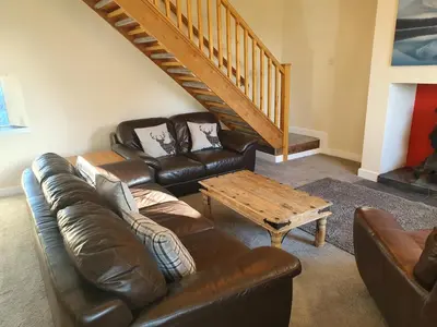 a living room with a leather couch and a coffee table at Lovely Cottage on Hadrians Wall 12 Miles From Carlisle in Carlisle