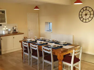 a dining room table with chairs and a clock on the wall at Lovely Cottage on Hadrians Wall 12 Miles From Carlisle in Carlisle