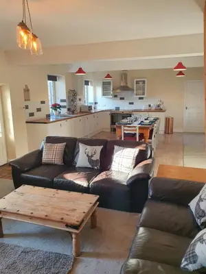 a living room with leather couches and a kitchen at Lovely Cottage on Hadrians Wall 12 Miles From Carlisle in Carlisle
