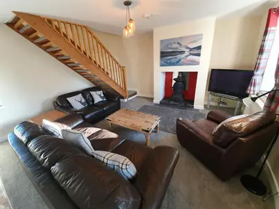 a living room with a leather couch and a table at Lovely Cottage on Hadrians Wall 12 Miles From Carlisle in Carlisle