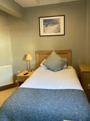 a bedroom with a bed with a blue blanket at The Sleepwell Inn in Workington