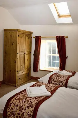 a bedroom with two beds and a window at DAIRY MAIDS COTTAGE in Seascale