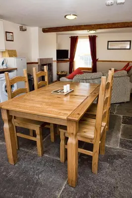 a wooden table and chairs in a living room at DAIRY MAIDS COTTAGE in Seascale