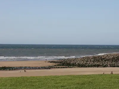 a beach with people on the sand and the ocean at Rowan Cottage in St Bees