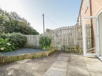 a wooden fence with a bench in a yard at Rowan Cottage in St Bees