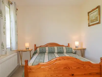 a bedroom with a wooden bed with two night stands at Rowan Cottage in St Bees
