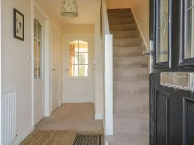 a hallway of a home with a white door and stairs at Rowan Cottage in St Bees