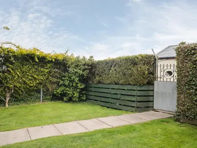 a garden with a fence and a bird feeder at Mousehole Cottage in Carlisle