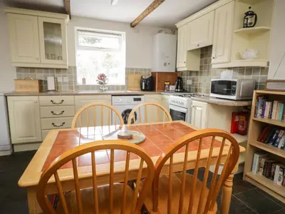 a kitchen with a wooden table and four chairs at Mousehole Cottage in Carlisle